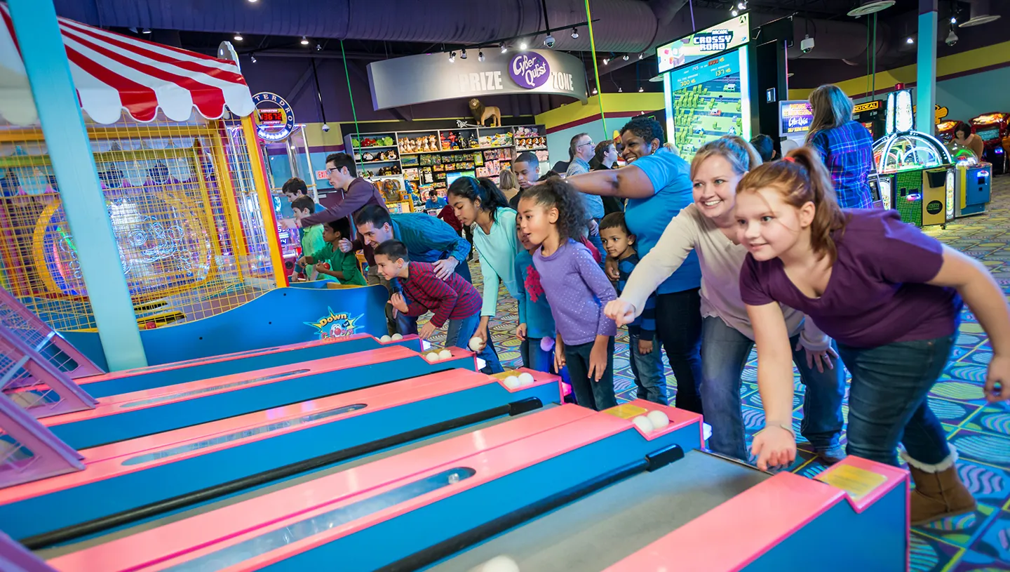Families rolling Skee-Ball side by side at Cyber Quest, with the Prize Zone behind them