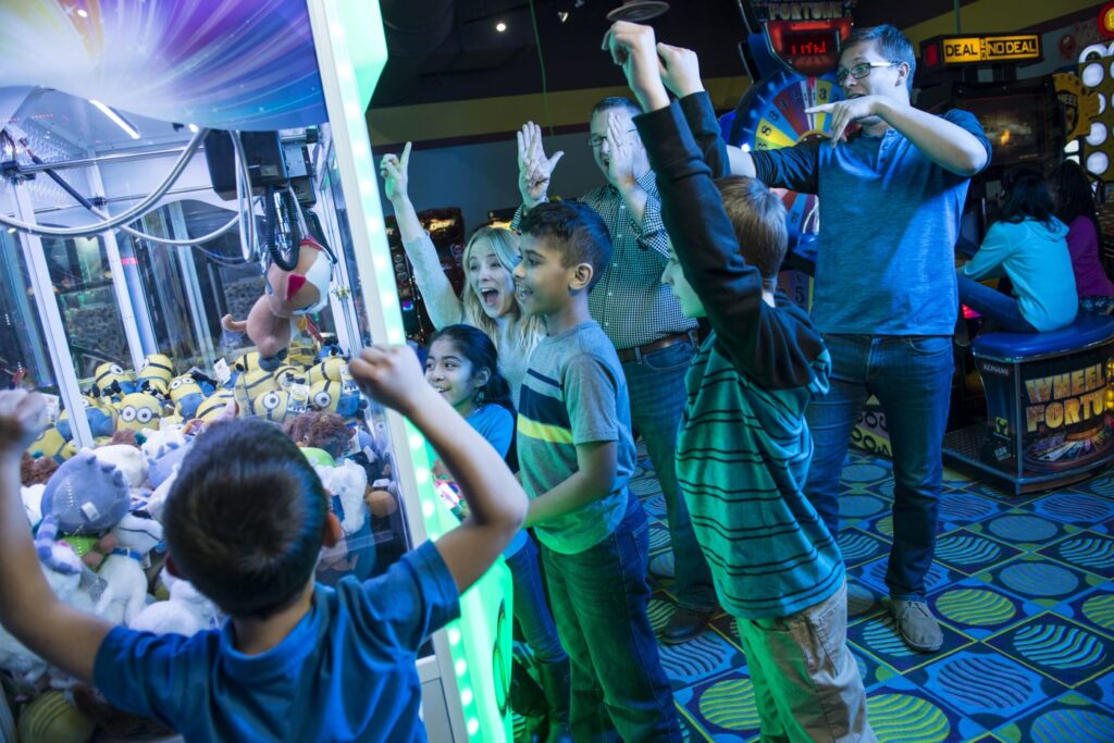 A family cheering as a boy wins a plush prize from a crane game at Cyber Quest