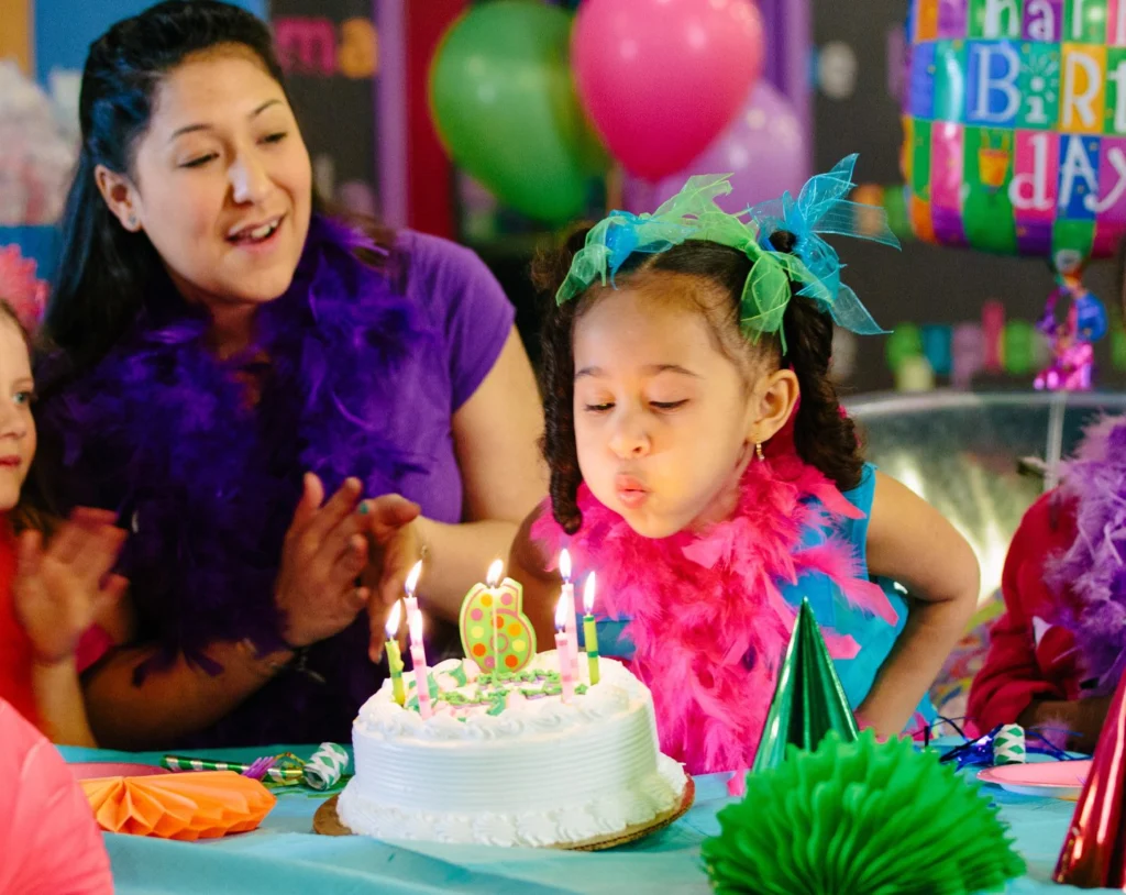 A girl blowing out the candles on her birthday cake at a Kids Quest party