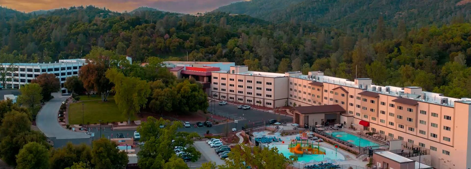 Aerial view of Black Oak Casino Resort in Tuolumne, California, with its hotel, pools and splash pad among wooded hills