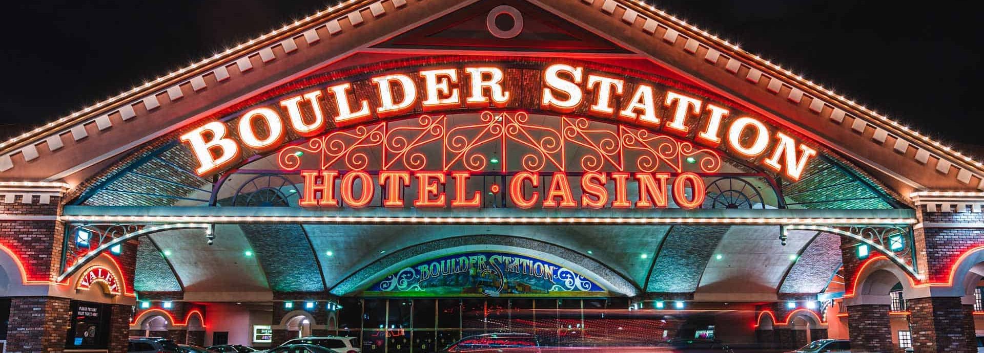 The glowing red neon Boulder Station Hotel Casino sign over the main entrance at night in Las Vegas