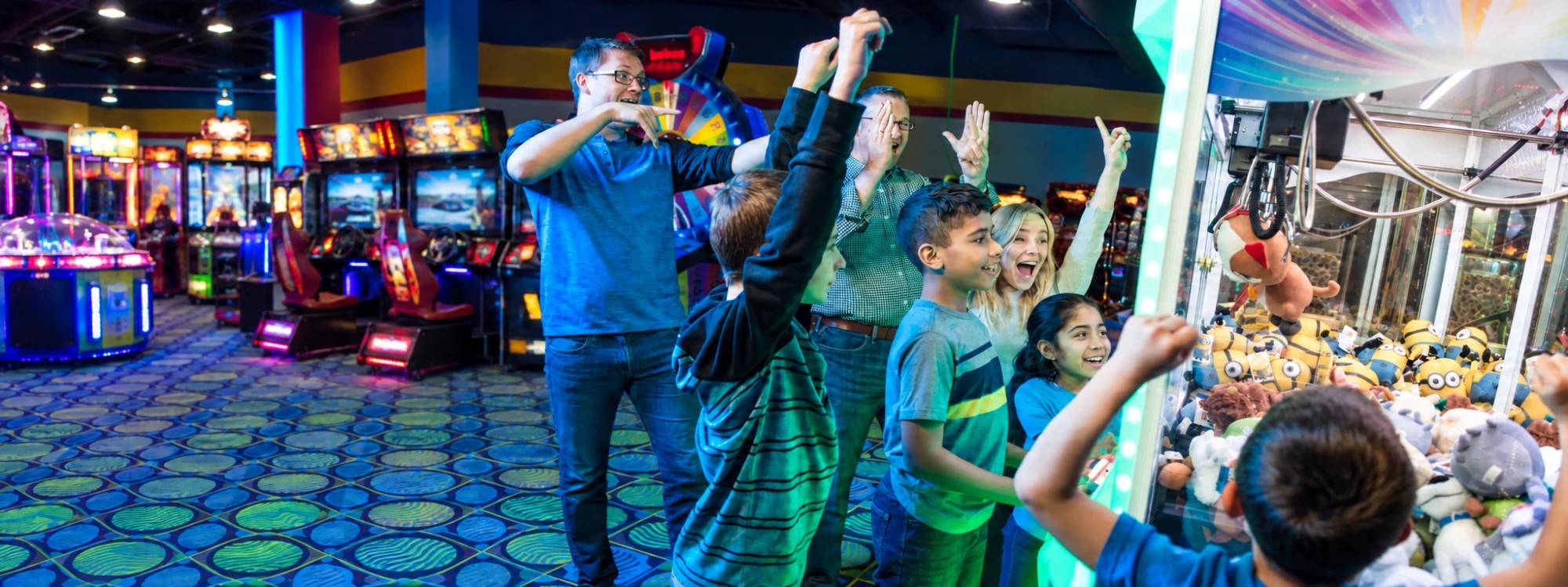 A child celebrating a claw machine win at Cyber Quest