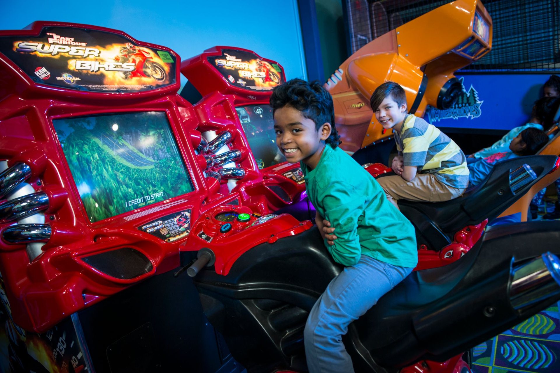 Two boys smile from the Super Bikes motorcycle racing games at Cyber Quest