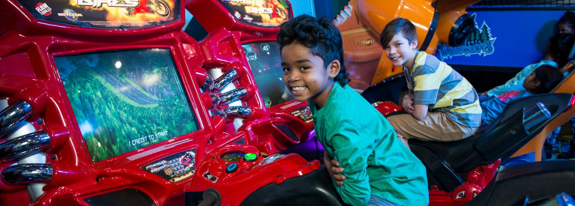 Two boys smile from the Super Bikes motorcycle racing games at Cyber Quest
