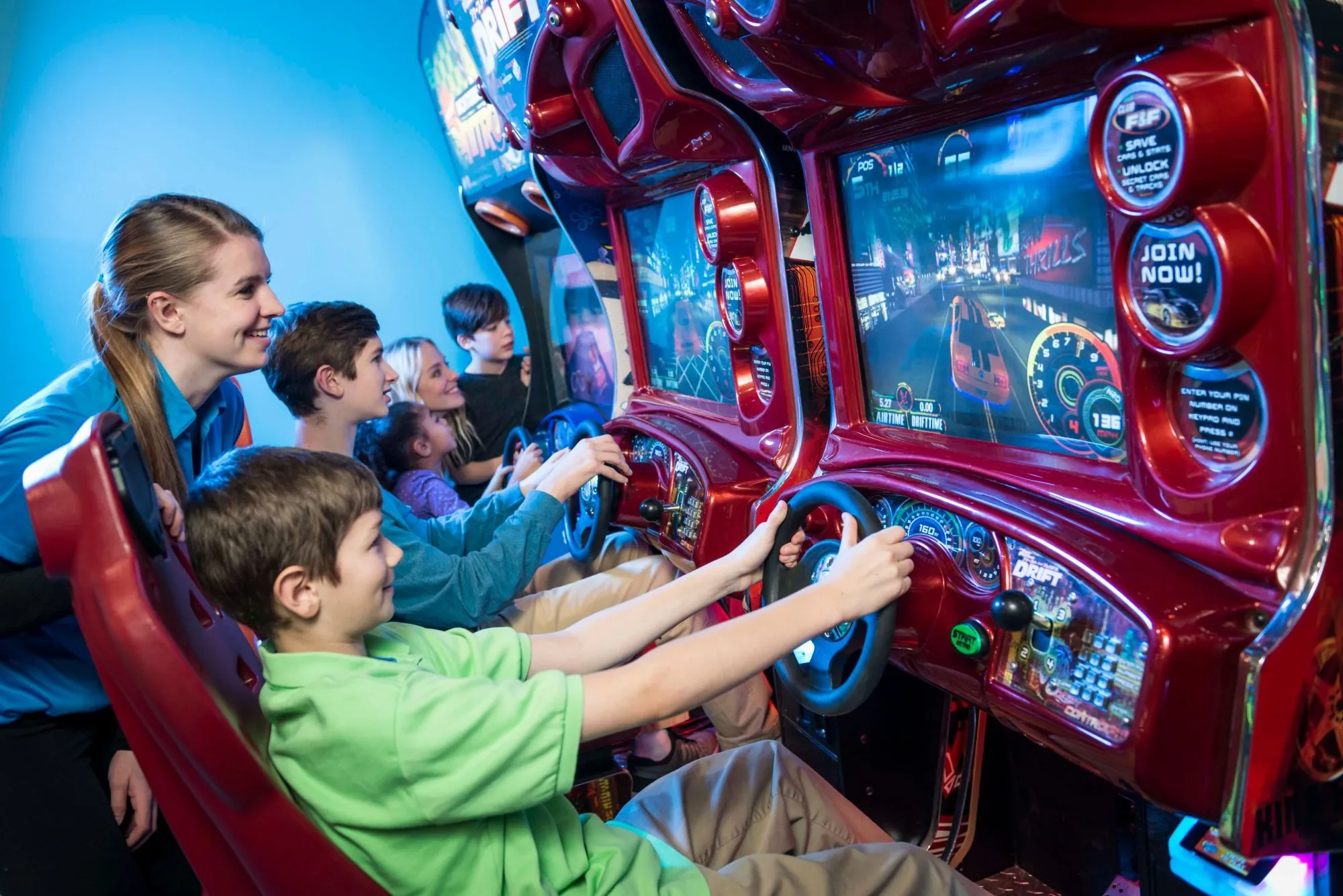 A Cyber Quest team member cheers on a family racing side by side at the sit-down racing games