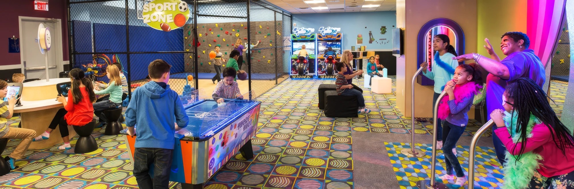 Kids play at the iPad Station, air hockey, the Sports Zone climbing wall and Super Bikes while a Kids Quest teammate cheers on girls at the Karaoke Star Stage