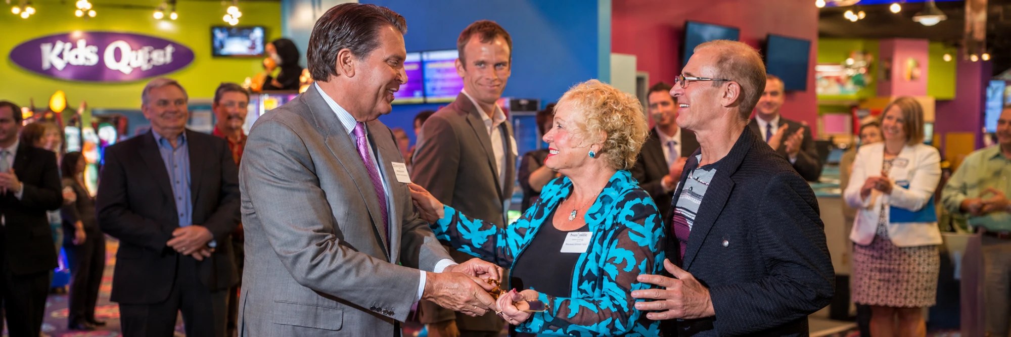 Kids Quest leaders and resort partners smile and shake hands as guests applaud at a Kids Quest center opening